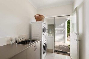 A laundry area with a washing machine, a sink, and a basket on a cabinet.