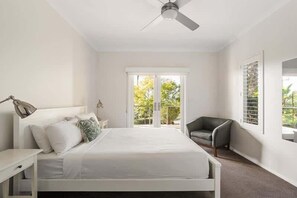 Une chambre à coucher avec un lit, une chaise, un bureau et un ventilateur de plafond.