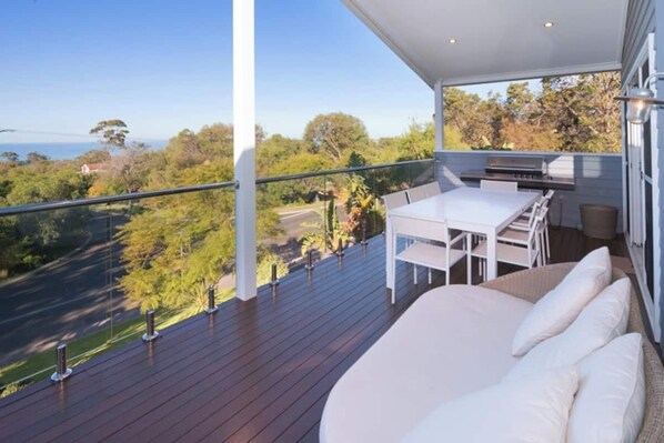 Enjoy a balcony with a view of the surrounding greenery, featuring a table, chairs, sofa, and grill.