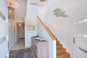 Staircase leads to an upper level, with a console and artwork adding to the space's aesthetic.