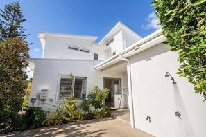 A two-story house with a white exterior, a covered porch, and a small garden area.
