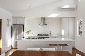 A modern kitchen with a central island, stainless steel appliances, and white cabinetry.