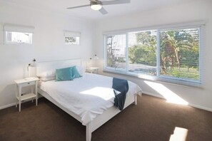 Cozy retreat with a single bed, ceiling fan, and large window offering a view of the surrounding greenery.