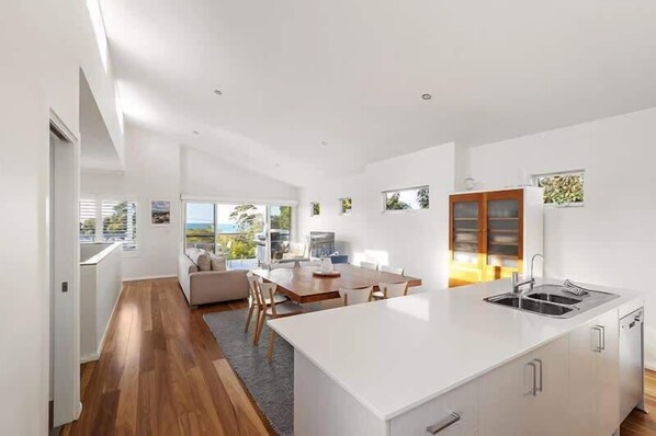 A modern kitchen with a large island, a dining area with a table and chairs, and a view of the outdoors.