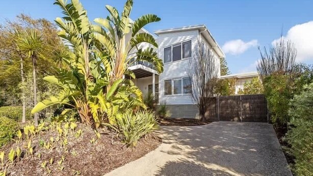 A two-story house with a driveway, surrounded by banana trees and other vegetation. - Casa Bianca—Oceanview Beachside Escape (Dunsborough)