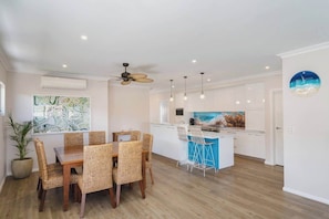 A modern kitchen with white cabinets, a blue island, and pendant lighting.