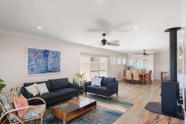A modern living room with a black sofa, a wooden coffee table, a wicker chair, and a large abstract painting.