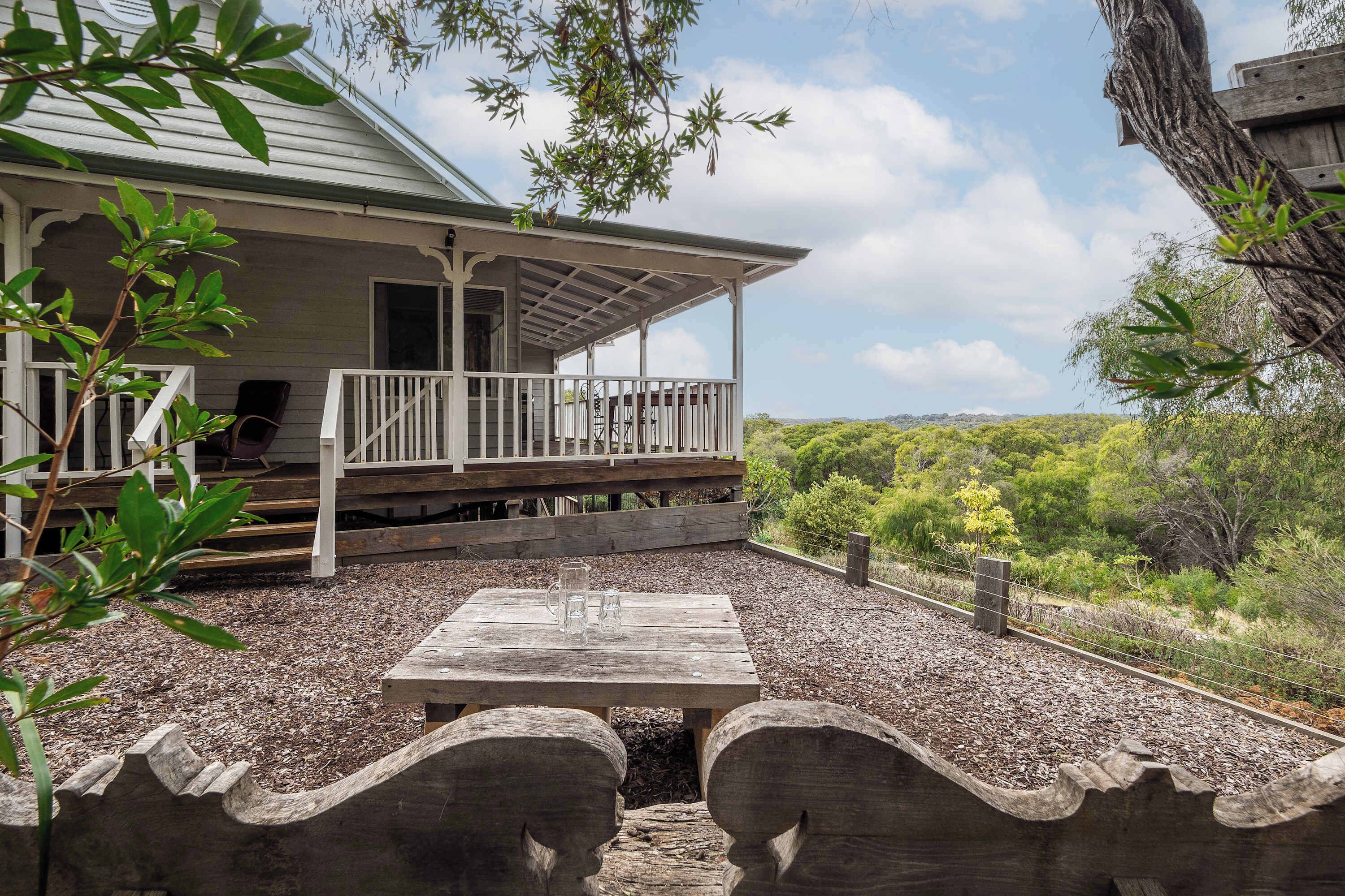 Une terrasse couverte avec une table et des chaises, une terrasse en bois et une vue sur le paysage environnant.