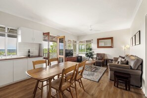 A spacious living area with a dining table, sofa, and TV.
