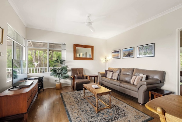 A living room with a sofa, coffee table, and a desk with a laptop.