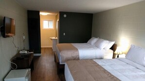A hotel room with two beds, a TV, a desk with a lamp, and a microwave. - Paddock Inn (Coleman)