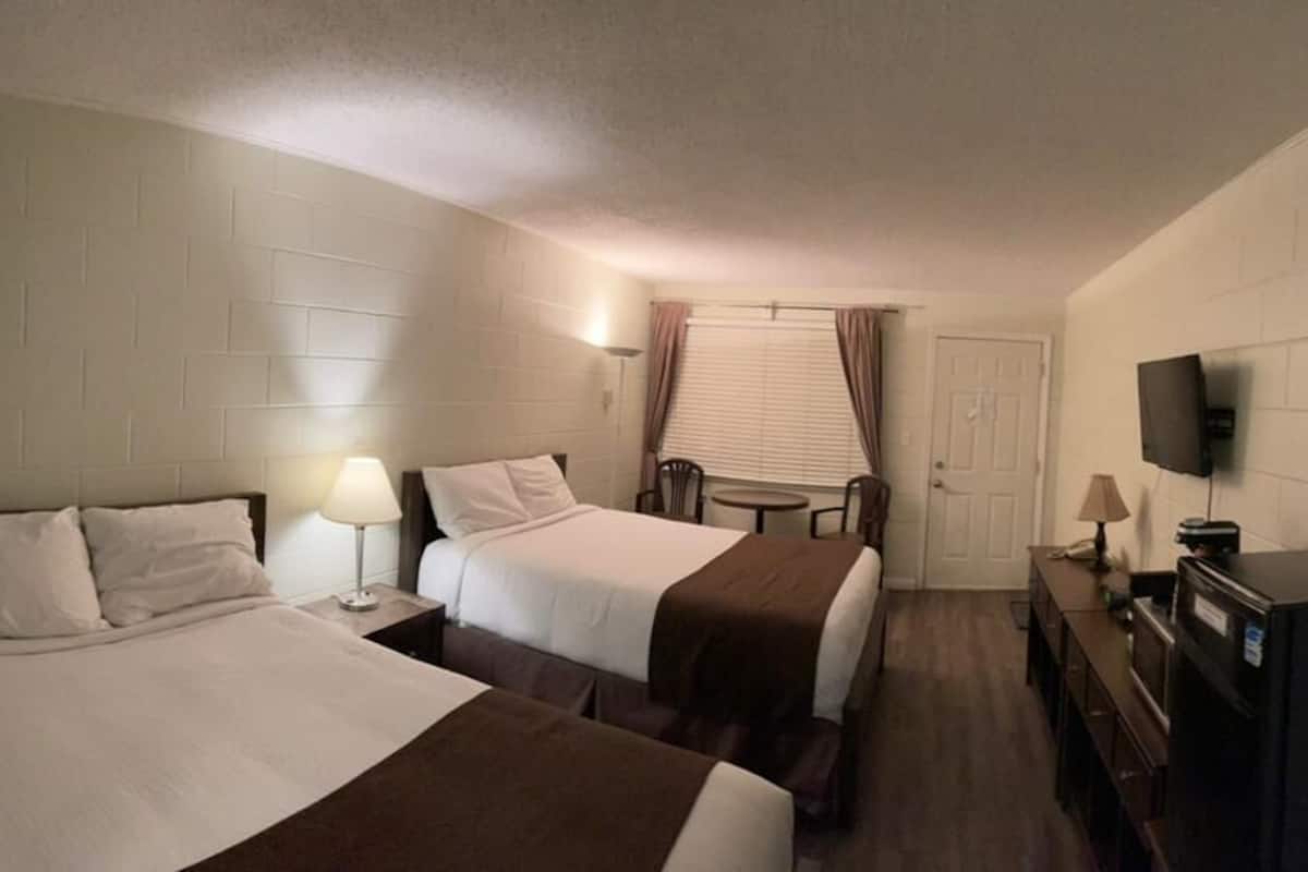 Quarto de hotel com duas camas, televisão, secretária e extintor de incêndio.