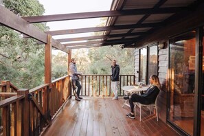 A wooden deck with a glass enclosure, a table, and chairs.