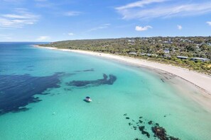 Une zone côtière aux eaux turquoise et limpides, avec une plage de sable et un petit bateau ancré près du rivage.