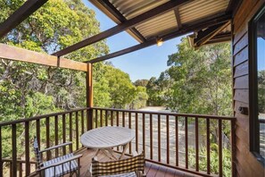 Une terrasse en bois avec une table et des chaises, entourée d’arbres.
