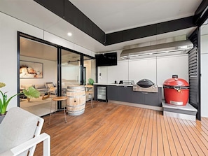 Une cuisine moderne dotée d’un barbecue intégré, d’un grand fumoir rouge et d’un plancher en bois.
