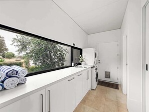 Une cuisine moderne dotée d’une grande fenêtre, de meubles blancs et d’un lave-linge encastré.