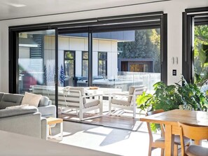 A modern living room with a sofa, chairs, a table, and a large sliding glass door leading to an outdoor area.