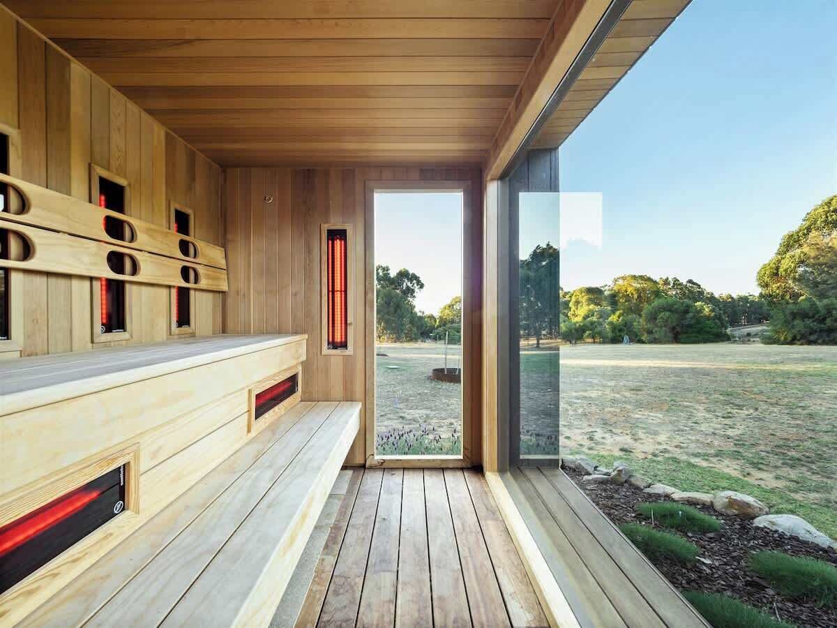A sauna with wooden benches and a glass door leading to an outdoor area.