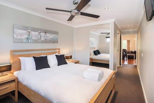 Ein Hotelzimmer mit Bett, Deckenventilator, einem Gemälde und einem Spiegel.
