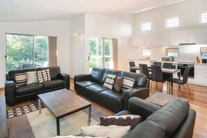 A modern living room with a sofa set, a coffee table, and a dining area with chairs and a table. - Villa on the Cape (Dunsborough)