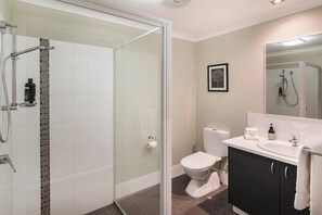 A modern bathroom with a glass-enclosed shower, a white toilet, and a black vanity with a mirror. - Villa on the Cape: Relaxed Hideaway near Town (Dunsborough)
