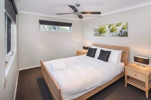 A bedroom with a bed, bedside tables, a ceiling fan, a window, and a wall-mounted artwork. - Villa on the Cape (Dunsborough)