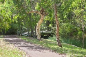 A paved path in a wooded area with a bridge over a body of water. - Villa on the Cape (Dunsborough)
