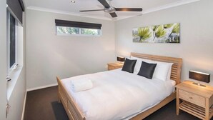 A bedroom with a bed, two bedside tables, a ceiling fan, a window, and a wall-mounted artwork. - Villa on the Cape: Relaxed Hideaway near Town (Dunsborough)