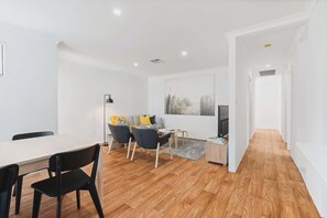 A modern living room with a dining area, wooden flooring, and a painting on the wall.
