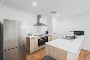 A modern kitchen with a stainless steel refrigerator, a built-in oven, a microwave, and a sink.