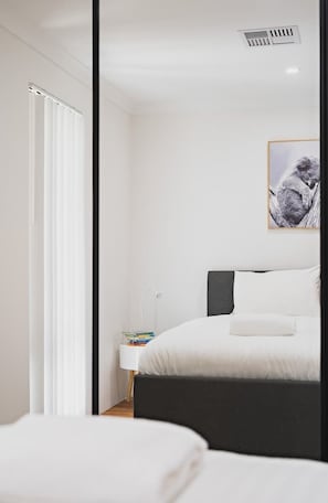 A modern bedroom with a bed, bedside table, and a framed picture on the wall.