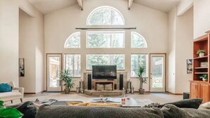 Un salón amplio con chimenea, ventanas grandes y una televisión.