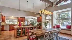 Una cocina amplia con suelo de madera, una isla central y un comedor con una mesa grande y sillas.