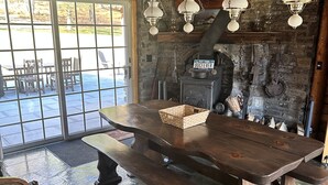 Un intérieur rustique avec une cheminée en pierre, une table en bois et des lampes suspendues.