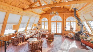 Un intérieur spacieux en bois, avec un plafond haut, de grandes fenêtres et une cheminée.