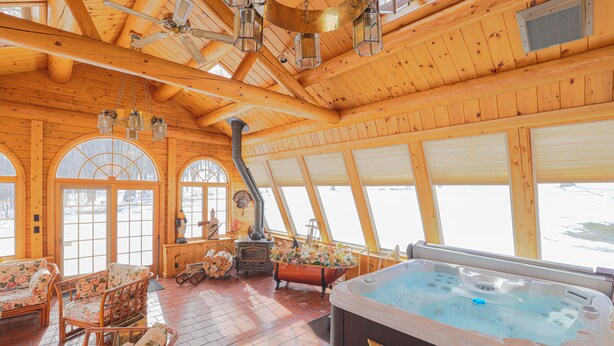 L’intérieur d’un chalet en bois, avec un jacuzzi, des meubles en bois et de grandes fenêtres.