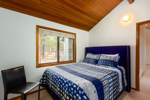 Quarto com uma cama grande, uma cadeira e janela com persianas.