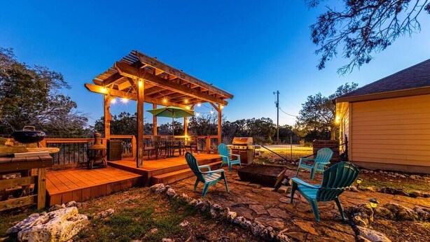 An outdoor patio with a wooden pergola, outdoor seating, and a grill area. - Hilltop Home: Canyon Lake~ Sleeps 12 •Gameroom •Firepit •1 Acre •RV/Boat Parking (Comal County)
