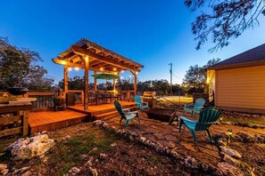 Un patio al aire libre con una pérgola de madera, mobiliario exterior y una zona de barbacoa.