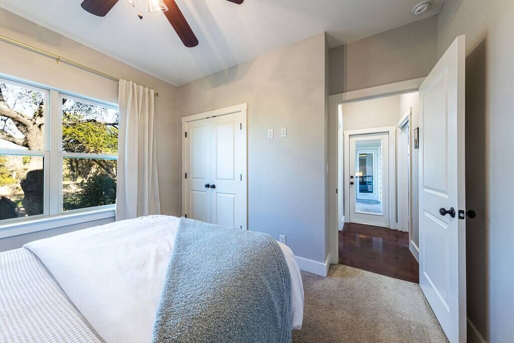 Une chambre à coucher avec un lit, une fenêtre et une porte donnant sur un couloir.
