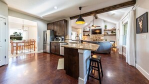 A spacious kitchen with dark wood cabinets, a granite countertop, and a large island with stools. - Hilltop Home: Canyon Lake~ Sleeps 12 •Gameroom •Firepit •1 Acre •RV/Boat Parking (Comal County)