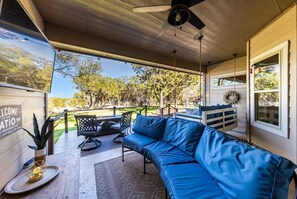 A covered outdoor patio with a blue sofa, a table, and chairs.