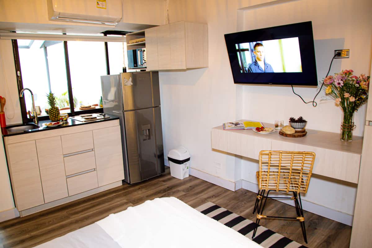 A compact kitchen with a refrigerator, microwave, and a small dining area with a chair and a table.