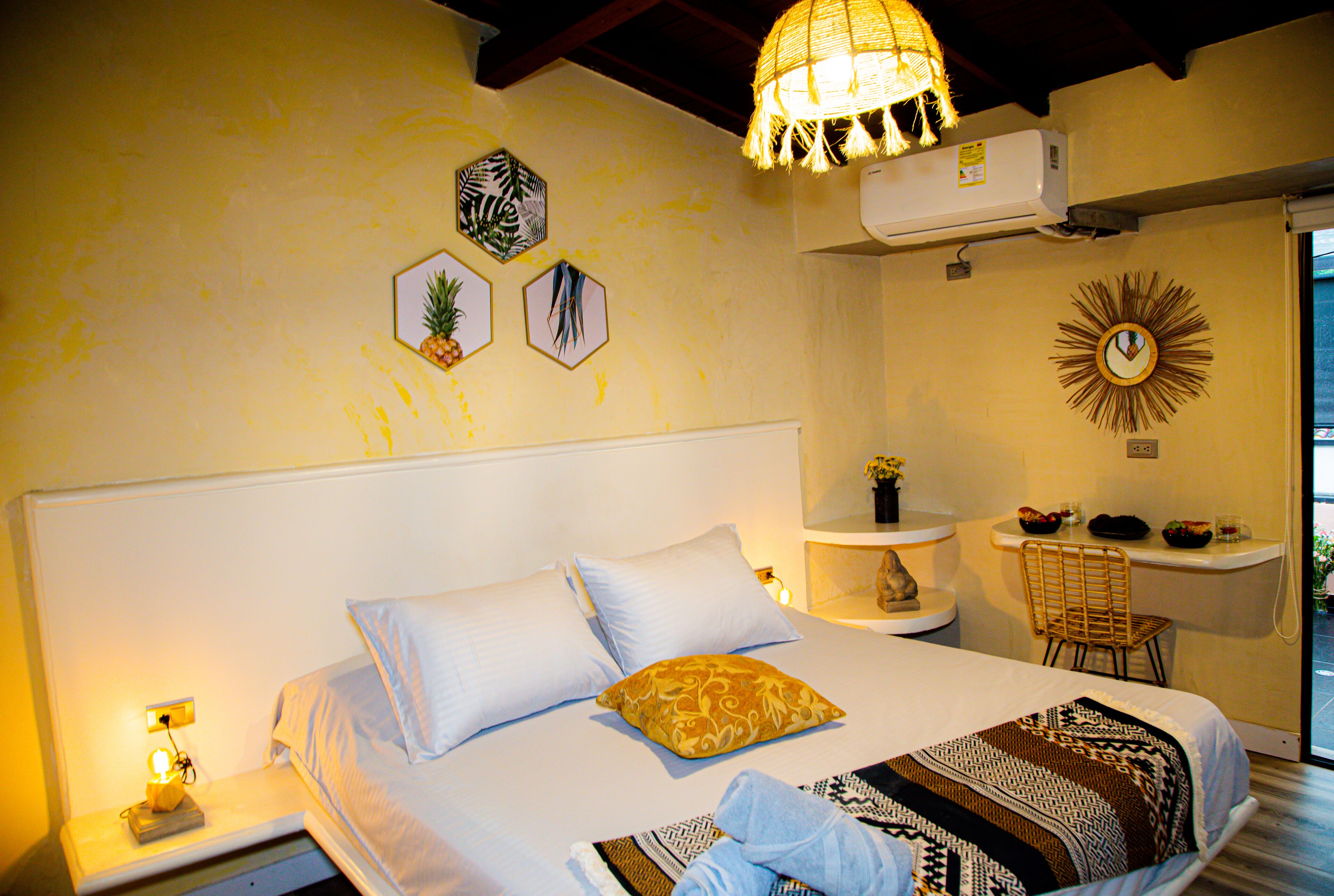 A bedroom with a bed, bedside table, lamp, wall decor, and a chair.