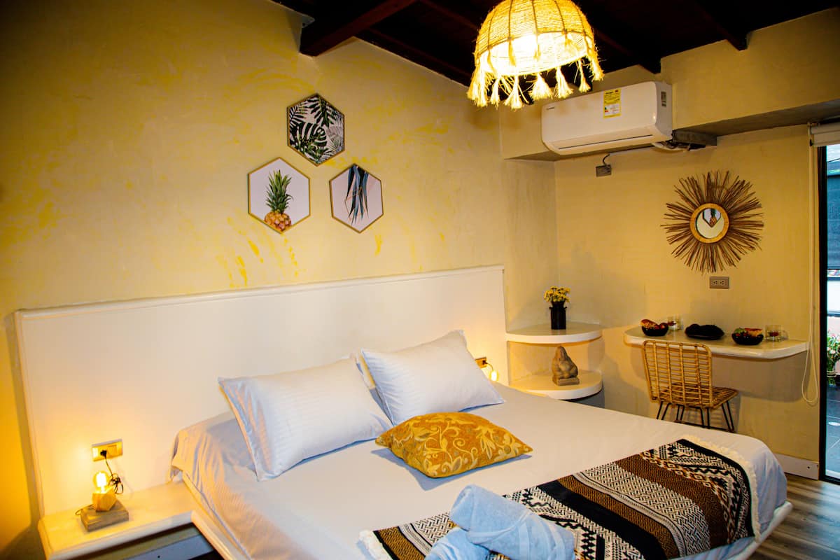 A bedroom with a bed, bedside table, lamp, wall decor, and a chair.