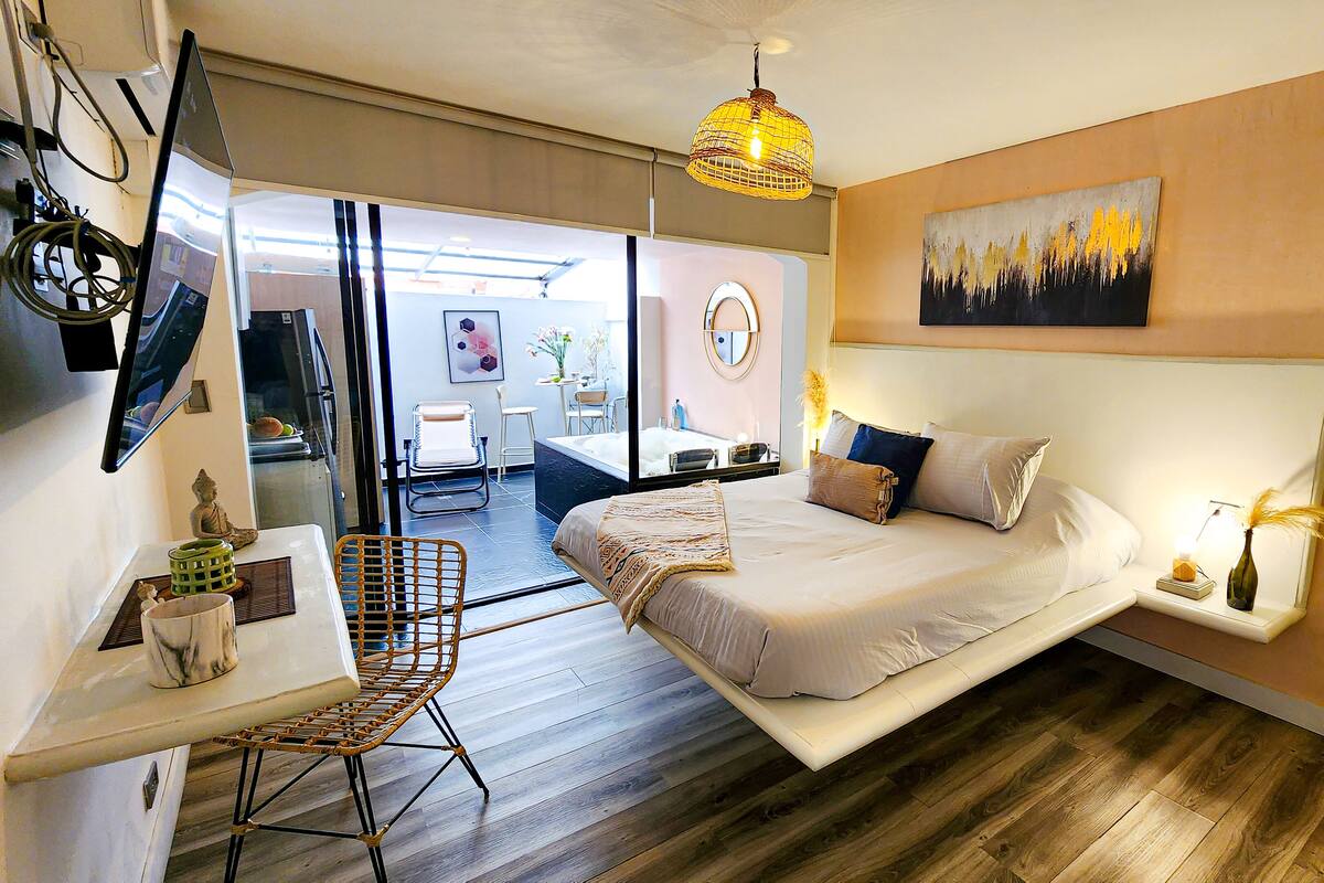 A modern bedroom with a large bed, a desk, and a chair.