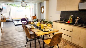 A modern kitchen with a dining area, wooden flooring, and a view to the living room. - Town House Jiwa in Provenza (Medellín)