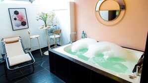 A bathroom with a bathtub, a chair, a small table with a vase, and a mirror on the wall. - Town House Jiwa in Provenza (Medellín)