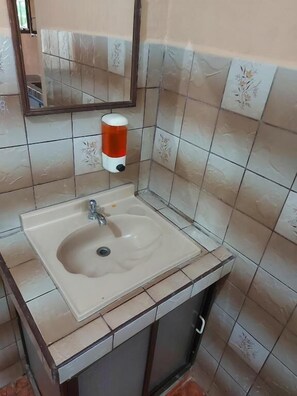 A bathroom with a sink, mirror, and hand soap dispenser. - Hotel Torrre Fuerte (Venecia)